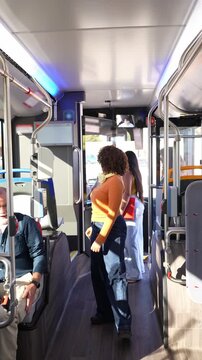 Young diverse people traveling by public transport. A woman paying the bus fare with a card using the contactless payment system validator