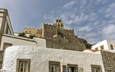 stone bell tower arched openings containing bells, part of a fortified structure with crenellated walls, and whitewashed in the Monastery of Saint John the Theologian of Patmos, Greece.