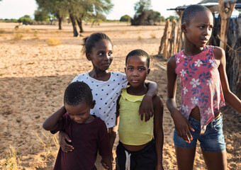 portrait african children in the village in the yard near the animal pen, sandy ground
