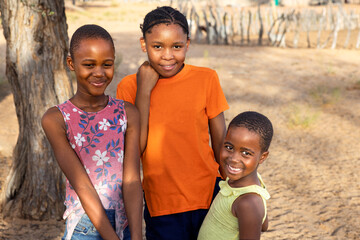 portrait african children in the village in the yard near the animal pen, sandy ground