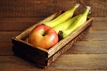 apples and bananas in a wooden crate