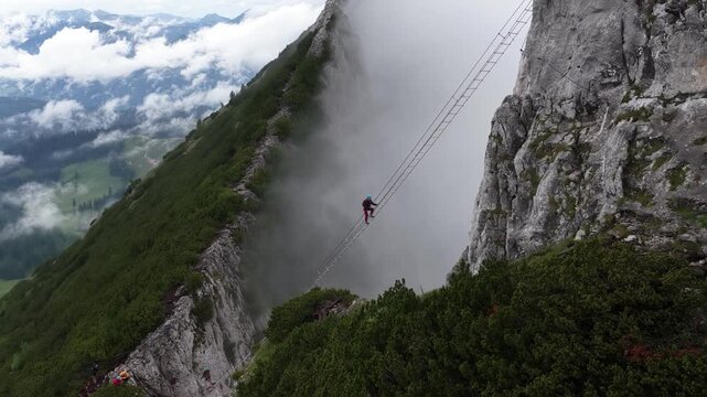 Hiker crossing a suspension bridge during a via ferrata in the mountains, Dachstein, Austria