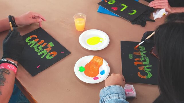 Lima, peru. 01 november 2025: hands painting colorful signs during an artistic workshop at a cultural food fair in peru