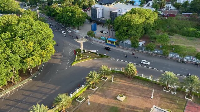 Aerial view of city streets with motorcycles and cars passing by during the late afternoon, capturing everyday urban traffic activity.