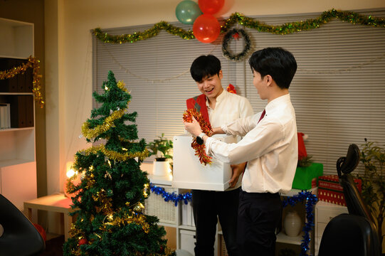 Two coworkers excitedly unbox Christmas decorations to prepare the office for the holiday celebration