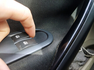 Hand pressing car window control switch inside vehicle