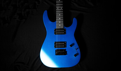 Obraz premium Blue electric guitar on dark stage background, symbol of rock music and creative inspiration, close-up detail with dramatic lighting