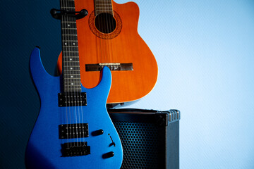 Electric and acoustic guitars with amplifier on light blue background. Music instruments with copy space for text or advertising design.
