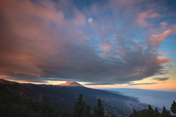 Vibrant sunset sky over Mount Teide in Tenerife, Canary Islands. Dramatic colorful clouds illuminate the volcanic landscape during the golden hour. A stunning scene capturing the beauty of Teide
