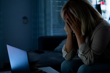 Stressed woman experiencing burnout working on laptop late at night