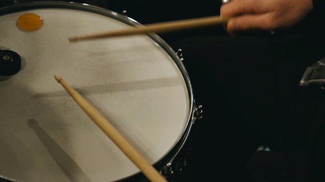 detailed shot of percussionist executing precise stick hits during warmup session in subdued