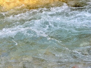 Energetic river water rushing with white foam and dynamic swirling motion