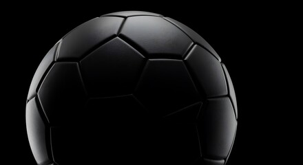 A black soccer ball with a textured surface on a black background