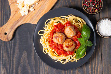 Delicious spaghetti with tasty meatballs in tomato sauce, and basil on background. Restaurant menu.