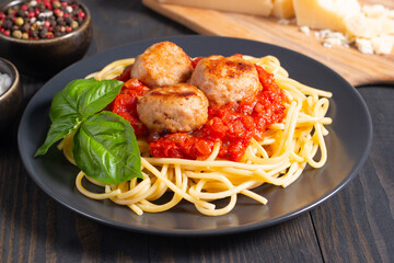 Delicious spaghetti with tasty meatballs in tomato sauce, and basil on background. Restaurant menu.
