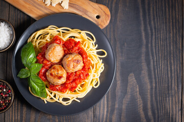 Delicious spaghetti with tasty meatballs in tomato sauce, and basil on background. Restaurant menu.
