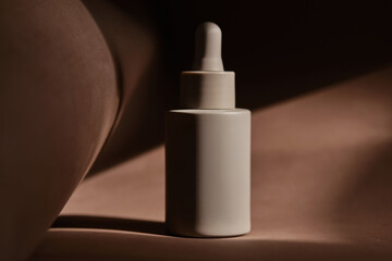 A bottle of face serum on a brown chocolate background.