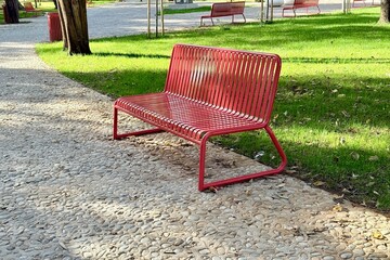 Empty red bench in sunny city park