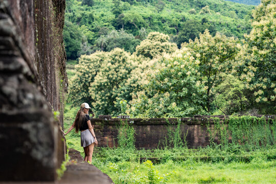 Woman exploring ancient temple ruins in tropical jungle