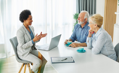 Senior couple having a meeting with an agent using a laptop computer , businesswoman, salesperson or doctor in his office