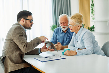 Obraz premium Senior couple having a meeting with an agent using a tablet computer , businessman, salesperson or doctor in his office
