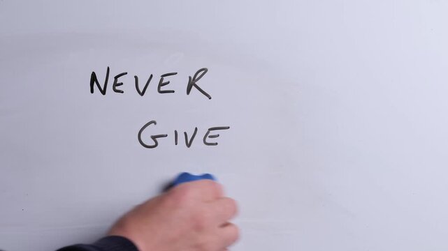 A person is writing Never Give Up in black marker pen on a whiteboard, perfect for business, motivation and inspiration themes