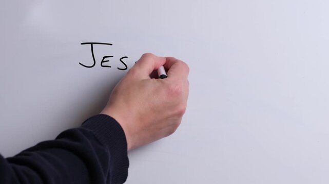 A person is writing Jesus is Lord in black marker pen on a whiteboard, perfect for Christian, religious themes, Church communications or faith presentations