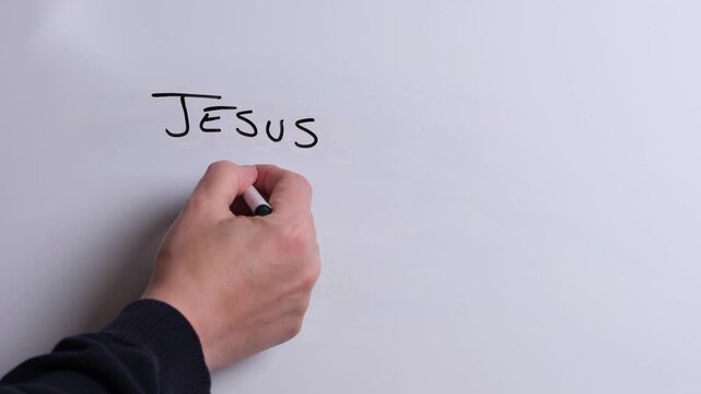 A person is writing Jesus is King in black marker pen on a whiteboard, perfect for Christian, religious themes, Church communications or faith presentations