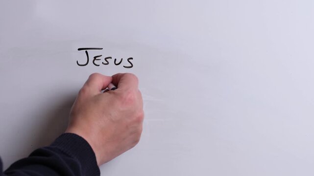 A person is writing Jesus is Perfect in black marker pen on a whiteboard, perfect for Christian, religious themes, Church communications or faith presentations