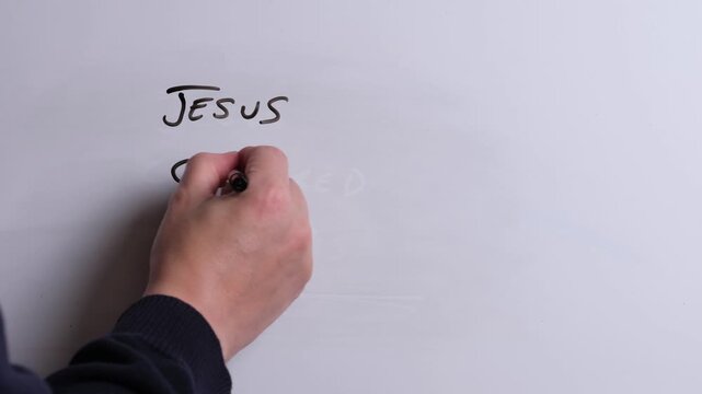 A person is writing Jesus Changes Everything in black marker pen on a whiteboard, perfect for Christian, religious themes, Church communications or faith presentations