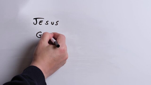A person is writing Jesus Guides Me in black marker pen on a whiteboard, perfect for Christian, religious themes, Church communications or faith presentations