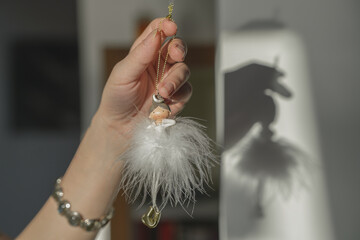 Delicate Handmade Doll Ornament with White Feathered Skirt Held in a Hand, Casting a Soft Shadow on a Bright Background