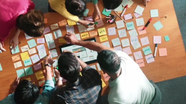 Aerial view of developer team discussing and showing digital program and writing by using Ux Ui design. Top down view of business people develop wireframe prototype for phone and computer. Symposium.