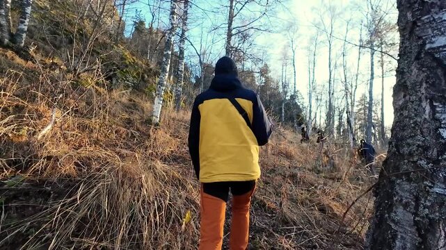 Person ascending rugged hillside at dusk, Adventurer challenges steep rocky trail during sunset hours, Individual determinedly traverses harsh mountain path illuminated by setting sun