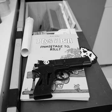 Black and white image of a toy gun resting on a book