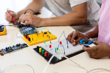 Fototapeta na wymiar Group of young students assembling electronic circuits with microcontrollers in a science lab. Hands-on STEM education, teamwork, and technology learning concept.