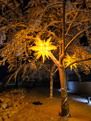 Christmas decorations, lanterns in the shape of Bethlehem's stars hanging on trees covered with snow.