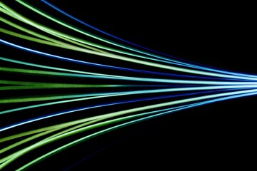 Abstract streaks of blue and green light moving rapidly on a black background