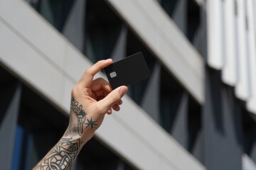 A Hand Holding a Sleek Black Card Against a Modern Architectural Background Showcasing Bold Geometric Lines and Minimalist Design