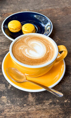 Bright coffee break with cappuccino and macarons on wooden table - concept of café, bakery, food blog