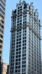 Obraz premium Historic skyscraper with ornate architecture amidst modern buildings in urban landscape concept of architecture firms, history publications, real estate agencies