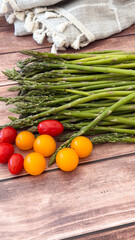Fresh asparagus and cherry tomatoes arrangement on rustic wooden surface for culinary and grocery business applications, concept of organic cooking