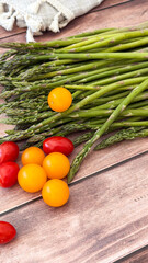 Fresh asparagus and colorful cherry tomatoes on wooden table - concept for farmers markets, organic stores, culinary blogs