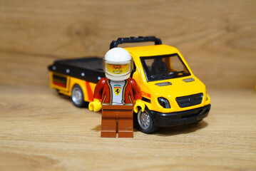 Obraz premium Lego minifigure with a yellow tow truck on a wooden surface