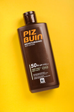 Bottle of Piz Buin Factor 50 SPF moisturising sun tan lotion against yellow background with copy space top view