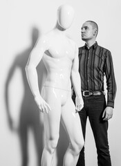 Man in a striped shirt and jeans standing next to a white male mannequin