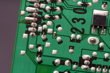 Circuit board in green with numerous silver solder points and electronic components in a repair...