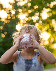 A child drinks water from a glass. Selective focus.