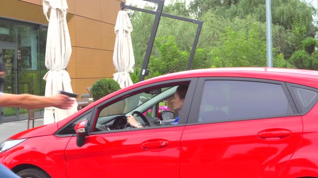 Young woman rides in red car and stoppes. Thief comes to her and take her away from machine. He sits inside in car and drives away.