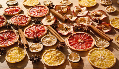 Various dried fruits and spices for winter and the Christmas season. Sliced ​​dried citrus fruits, apple rings with cinnamon sticks and star anise on wood. Preparations for christmas celebrations.